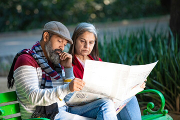 Indian senior couple reading news paper at park