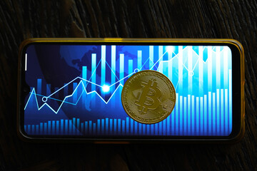 Bitcoin gold coin and defocused chart background. Virtual cryptocurrency concept.