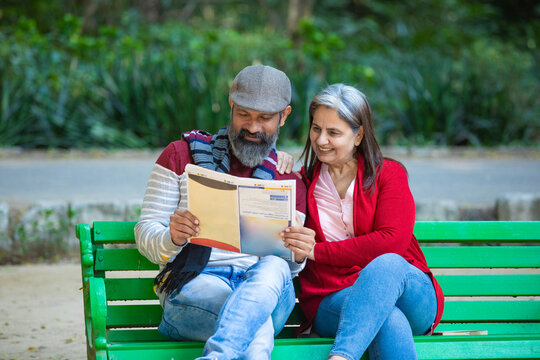 Indian senior couple reading news paper at park