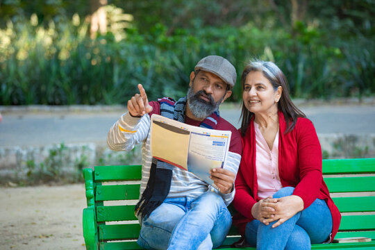 Indian senior couple reading news paper at park