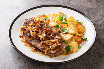 Original and Authentic German Zwiebelrostbraten with onion gravy and fried potatoes Bratkartoffeln closeup on the plate on the table. Horizontal