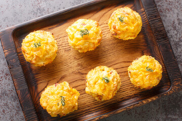 Tender homemade muffins made with potato, onion, bacon and cheddar cheese close-up on a wooden tray...