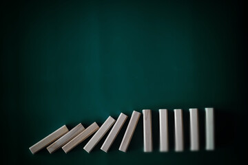 domino effect concept with wooden tiles blocked by hourglass with background