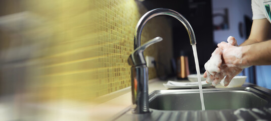 People are washing the dishes . Cleaning solution.A white bottle with dishwashing gel, sponges and rubber gloves on the background of a sink with dirty dishes.