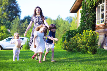 Obraz premium Young large family on a summer morning walk. Beautiful mother with children is playing in the park.