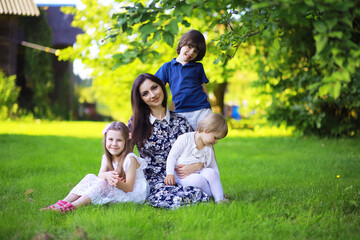 Obraz premium Young large family on a summer morning walk. Beautiful mother with children is playing in the park.