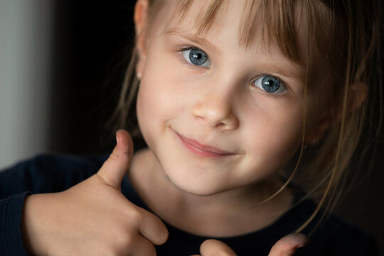 Portrait of a small child. Little girl with a smile and thumbs up. 
