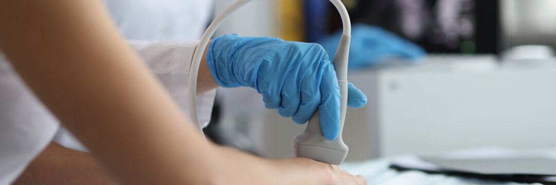 Doctor makes ultrasound of wrist in clinic closeup