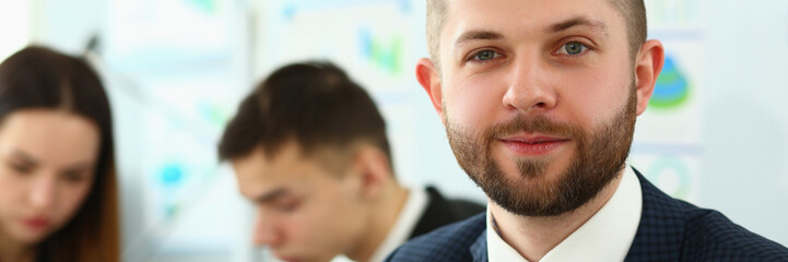 Portrait of smiling businessman with colleagues in a meeting in background in office