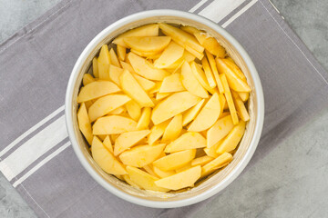 Apple slices in baking pan close-up on a kitchen table, flat lay with copy space. Apple cake, or apple pie recipe