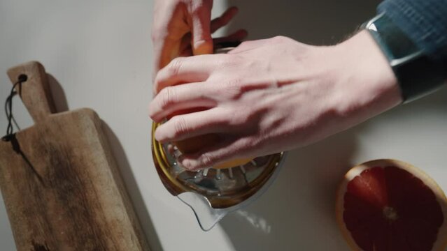 Bartender is pressing juice from grapefruit on a juice squeezer in kitchen for cocktail. Top Shot 4K