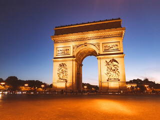 Arc de Triomphe illuminated at night with clear blue sky
