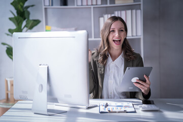 Sharing good business news. Attractive young businesswoman talking on the mobile phone and smiling while sitting at her working place in office and looking at laptop PC.