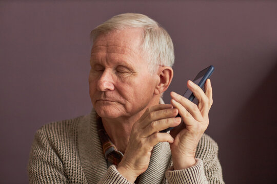 Blind man listening to audio assistant on smartphone