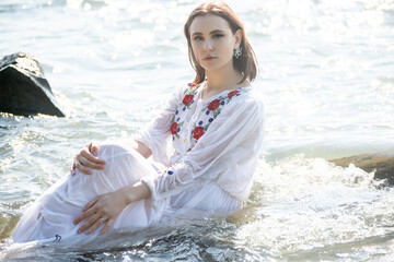 Young woman in white dress enjoys sea.