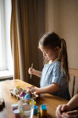 children paint eggs for easter at home
