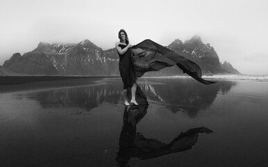 Stylish woman with waving cave on beach monochrome scenic photography. Picture of person with hills...