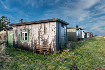 Fototapeta na wymiar Tipperne nature reserve small fishing cottages and huts in a rural landscape at Rinkoebing fjord in Denmark