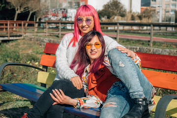 girl couple relaxed on gay pride rainbow painted bench