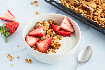 Homemade green buckwheat and nuts granola with coconut yogurt and strawberries in breakfast bowl. Healthy alternative food concept.