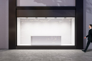 Man walking by evening empty shop window with podium inside for your product presentation on...