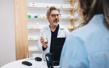 Mature pharmacist assisting a patient over the counter