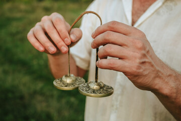 Indian tingsha bells for meditation and yoga in the hands of a man, sound vibrations for healing...