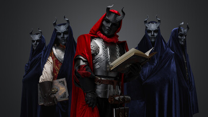 Portrait of dark cult members dressed in robes and their leader holding book.