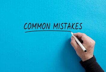 Male hand underlines the word Common Mistakes on blue background.