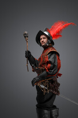 Fototapeta premium Shot of conquistador explorer dressed in plumed helmet and red attire holding torch.