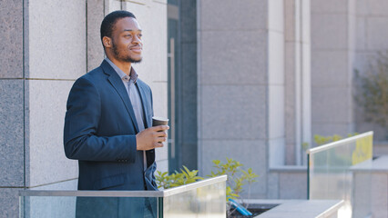 African American businessman entrepreneur office worker manager man business guy male employer standing on balcony resting at workplace finished work holding tea coffee thinking dreaming relaxing