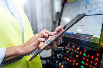Hands of engineer using tablet PC by machine in industry