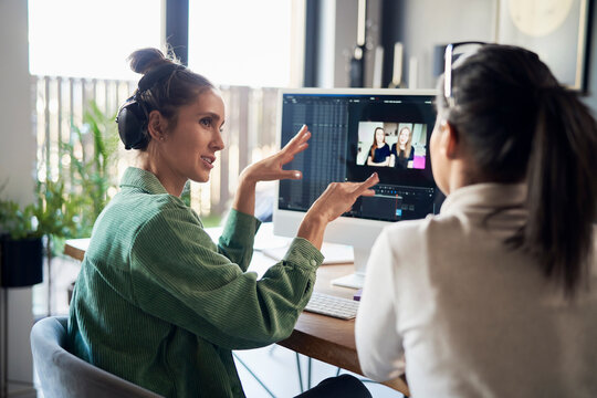 Freelancer explaining colleague over desktop PC at home office