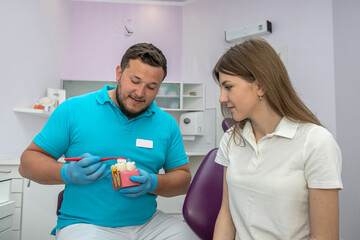 Fototapeta premium young dentist conducts a consultation for a girl with a sore tooth at his appointment.
