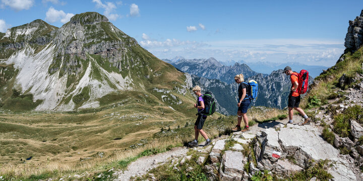 Man and women with backpack hiking towards Rifugio dal piaz on sunny day at Dolomites, Italy