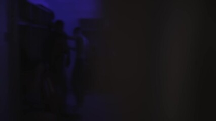 Football players change clothes in dark locker room before soccer match. Blurred. Men put on their sports uniforms strip, tracksuit in dressing room with blue lighting. Cloakroom. Shaky handheld shot