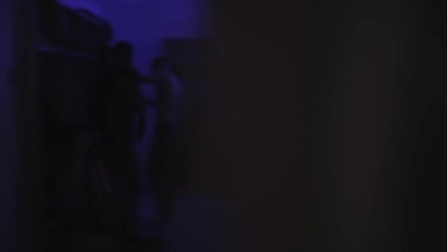Football players change clothes in dark locker room before soccer match. Blurred. Men put on their sports uniforms strip, tracksuit in dressing room with blue lighting. Cloakroom. Shaky handheld shot