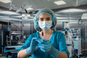 Obraz na płótnie Canvas Attractive female doctor holding syringe in operating room for patient.
