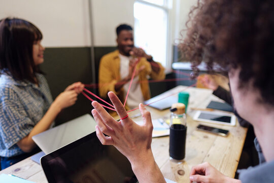 Business colleagues playing cat's cradle at workplace
