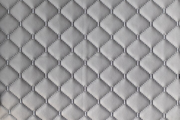 Texture of genuine leather upholstered furniture. Form rhombus. Gray bulk fabric for the background.
