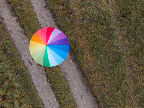 Woman with multi colored umbrella on footpath