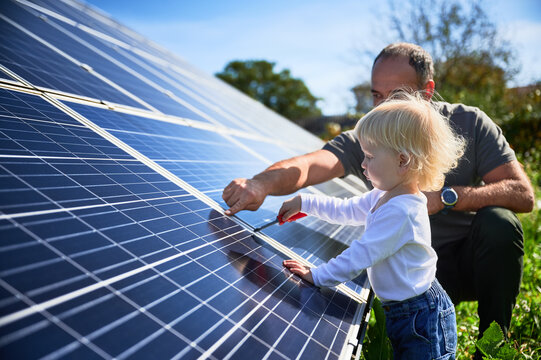 Man showing his small child the solar panels during sunny day. Father presenting to son modern energy resource. Little steps to alternative energy.
