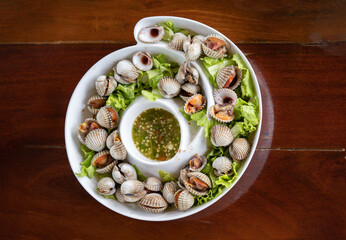 On the platter, there is cockle, juicy meat and veggies. Consume seafood sauce.