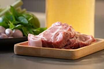Raw Pork is prepared for Cook, It is on wood plate on black granite kitchen counter tabletop, shot by studio light.
