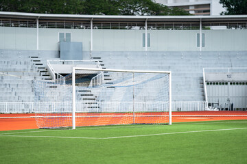 Fototapeta premium Goal area of artificial grass or turf court yard in front of an empty grand stand and entrance - exit main door.