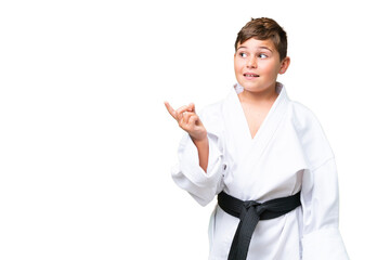 Little caucasian kid doing karate over isolated chroma key background intending to realizes the solution while lifting a finger up © luismolinero