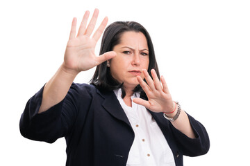 Scared businesswoman making stay away gesture with palms