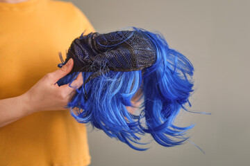 woman holds a bright purple wig in her hands. Womens beauty concept