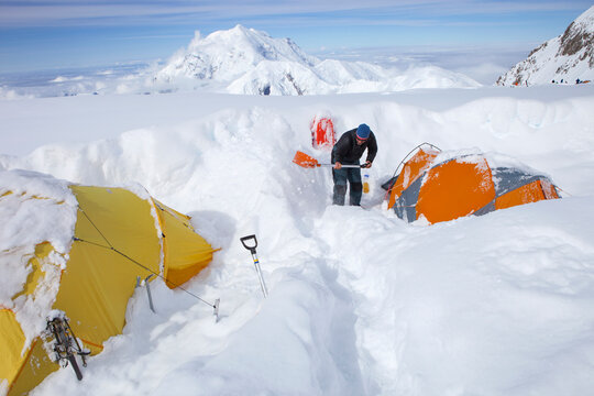 A Mountain Ranger is digging out tents after a snowstorm covered them during the night in 14k camp on Mount McKinley, Alaska.
