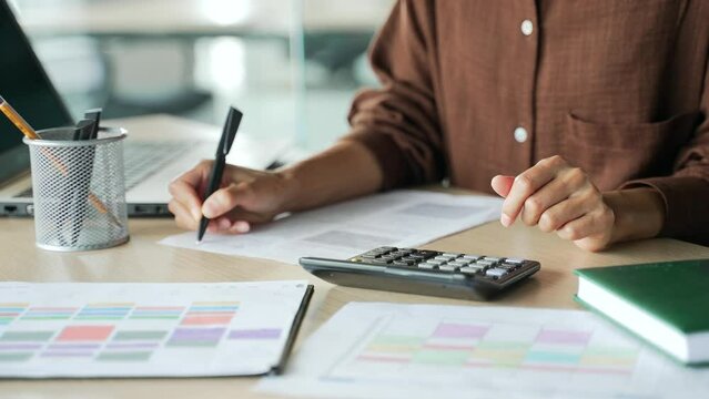 Close up hands of accountant clerk work with papers at desk in modern glass office Concentrated bookkeeper count financial report on calculator with documents and laptop computer at workplace indoors